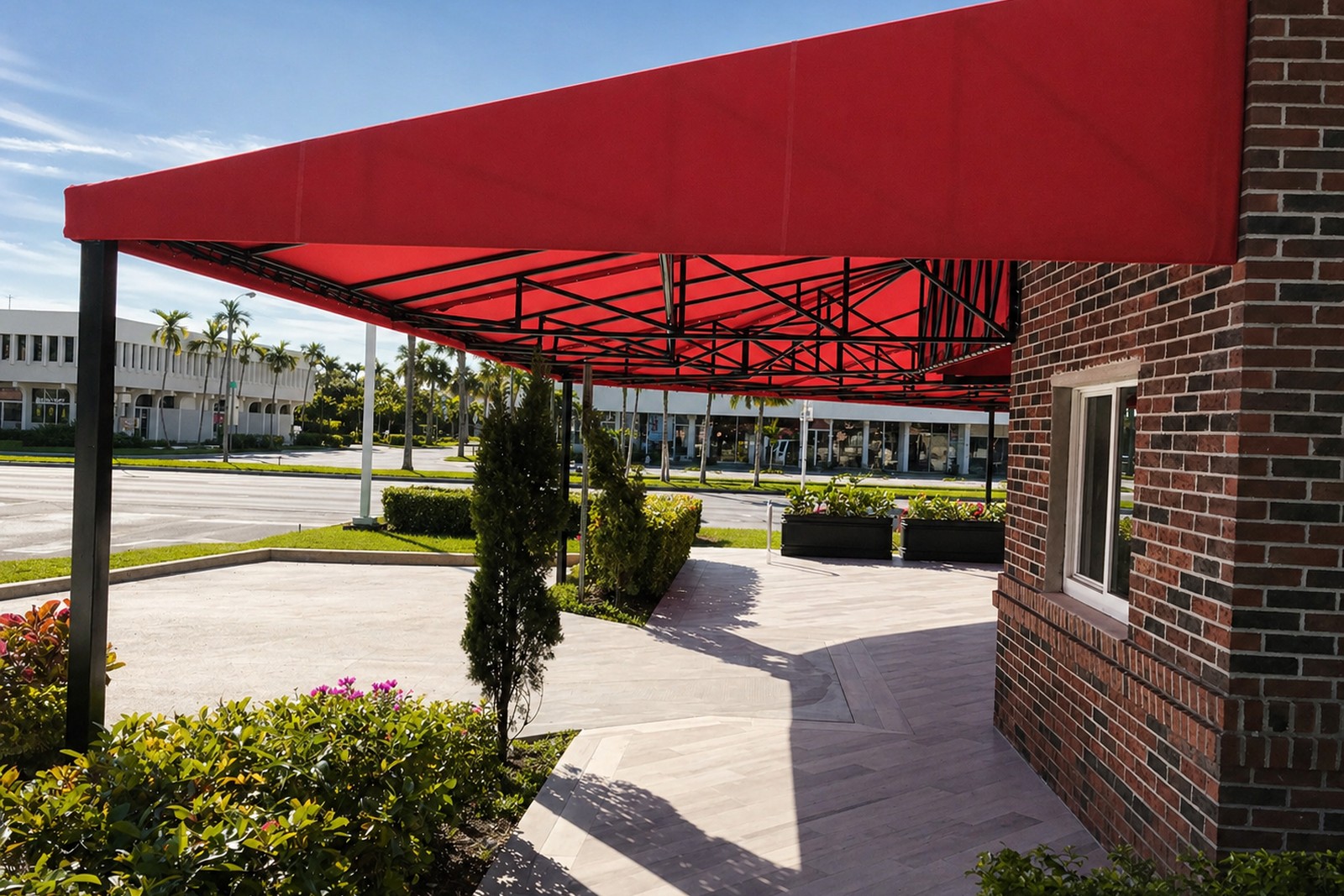 Looking out from beneath Vickys long red awning across an empty parking lot toward a strip plaza with palm trees.